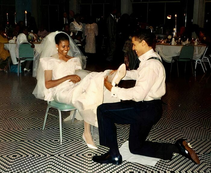 A groom kneels, smiling at his bride, capturing true happiness at their wedding reception.