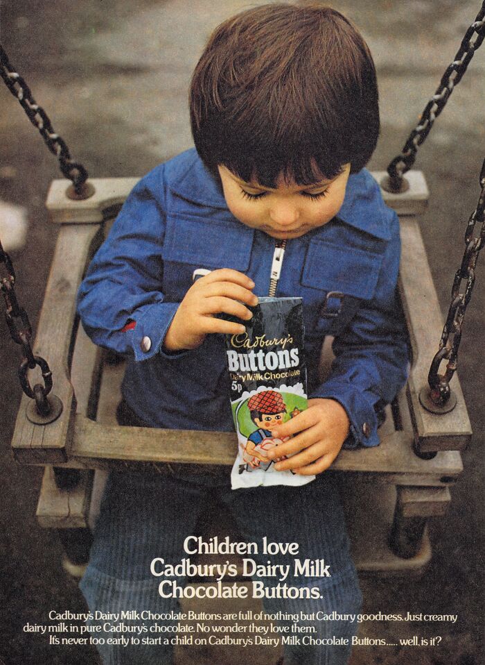 Child holding Cadbury's Dairy Milk Chocolate Buttons in a vintage-commercial setting on a swing.