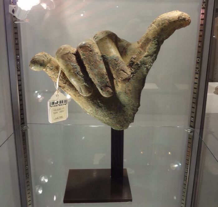 Ancient artefact resembling a hand gesture, displayed in a glass case, showcasing its preserved condition.