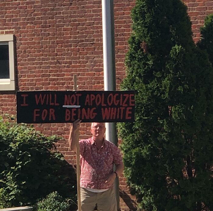 Hombre sosteniendo cartel con mensaje polémico, representando actitud prepotente; ejemplo de un "Karen masculino".