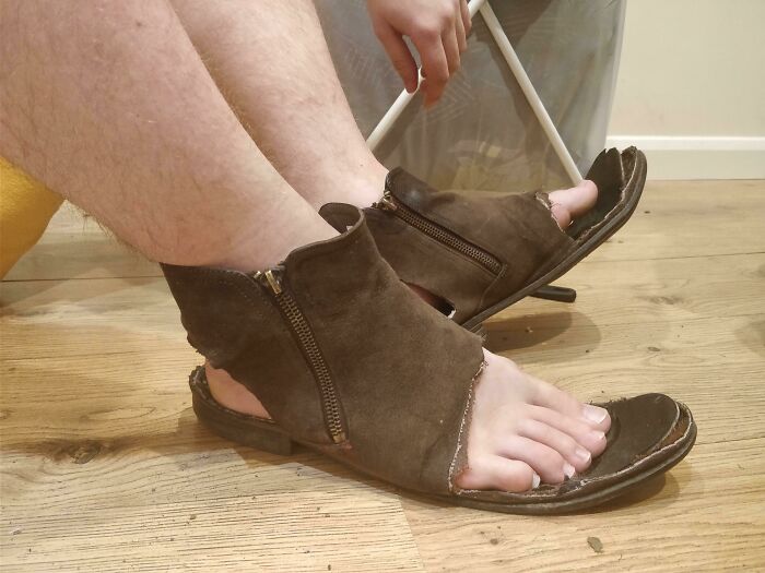 Worn-out sandals with zippers on a wooden floor, illustrating annoying boyfriends' husbands' questionable fashion choices.