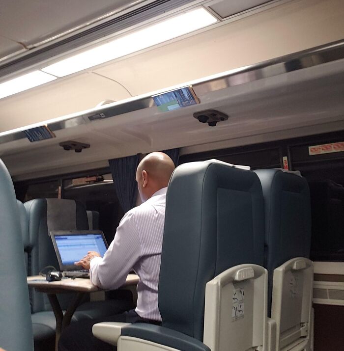 Hombre trabajando en su laptop en el tren, representando actitudes de «Karen masculinos».