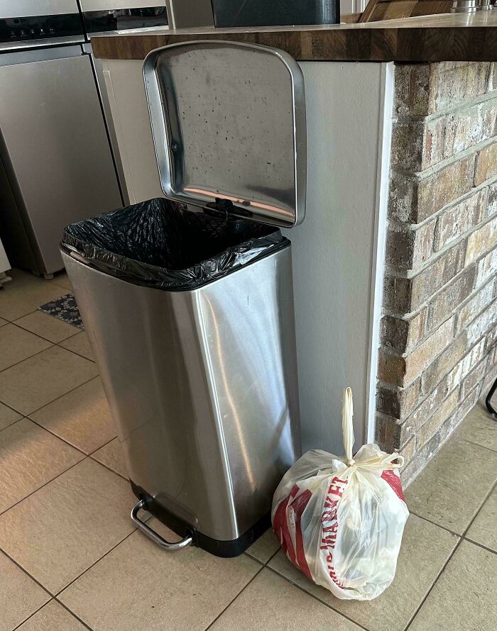 Trash can with lid open, garbage bag left on the floor, illustrating habits of annoying boyfriends or husbands.