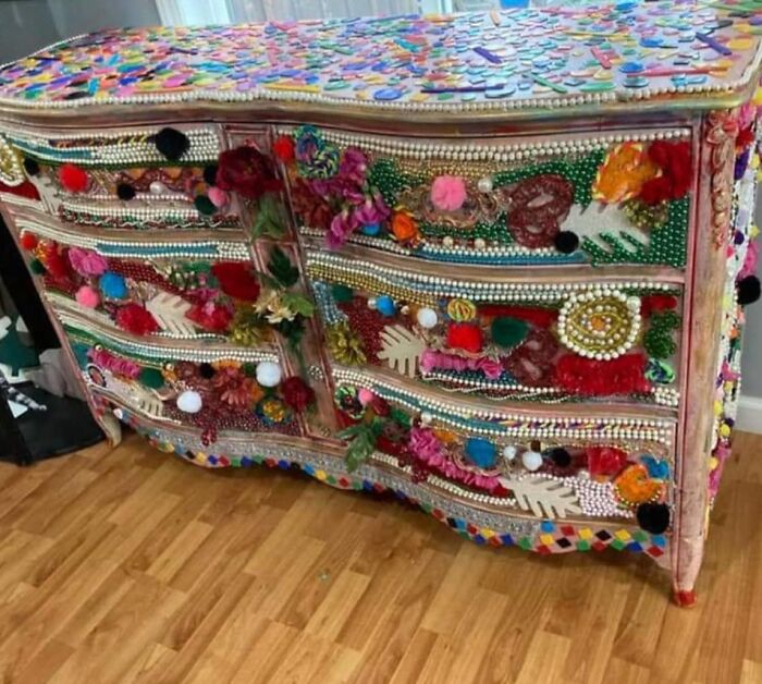 Colorful dresser with excessive decorations, featuring beads, pompoms, and artificial flowers, exemplifying horrendous DIY projects.