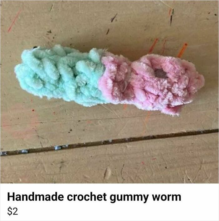 DIY craft project of a handmade crochet gummy worm in pink and green yarn on a wooden surface.