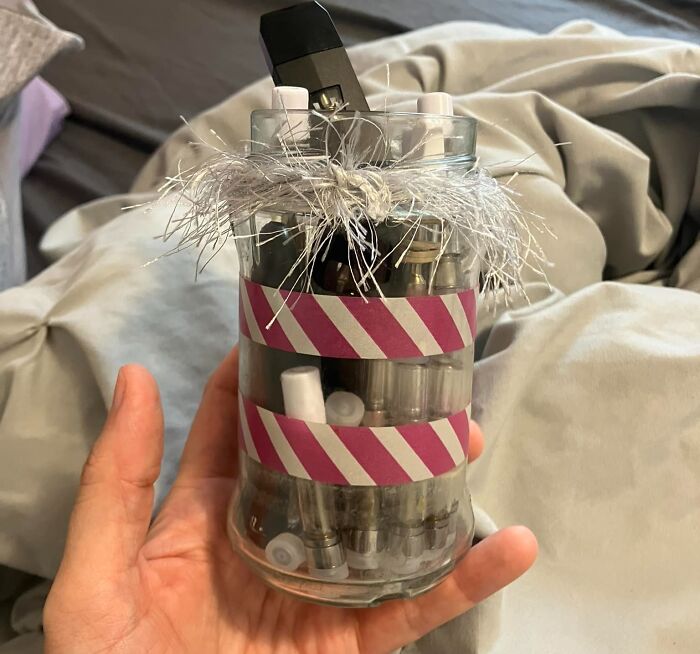 DIY project using a jar with pink striped tape and silver tinsel, filled with miscellaneous items, showcasing craft shaming.