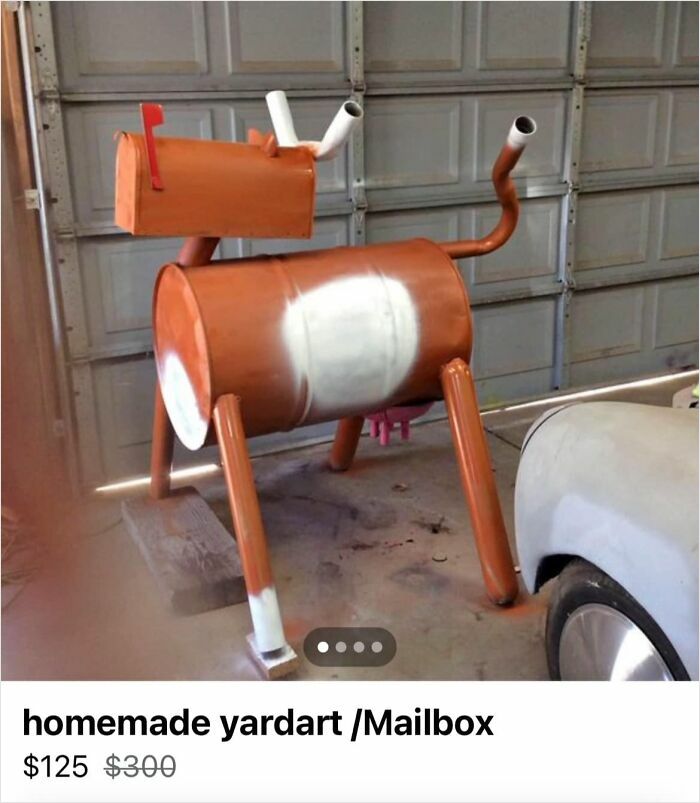 Bizarre DIY mailbox made from metal drums and pipes, painted orange and white, in garage setting.