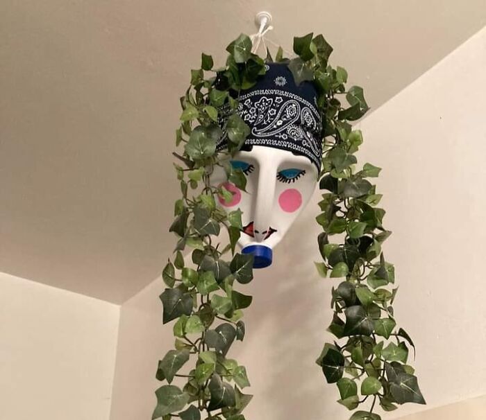DIY project with a painted face planter and trailing vines, creating a whimsical hanging decor piece.