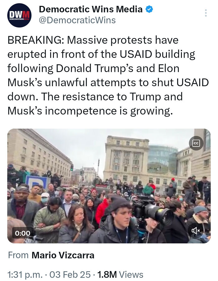 Crowd protesting in front of USAID building captured in a tweet showing courage to speak out during tense political moment.