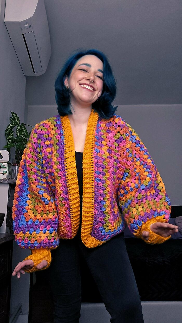 Person wearing a colorful crocheted cardigan, showcasing a DIY project.