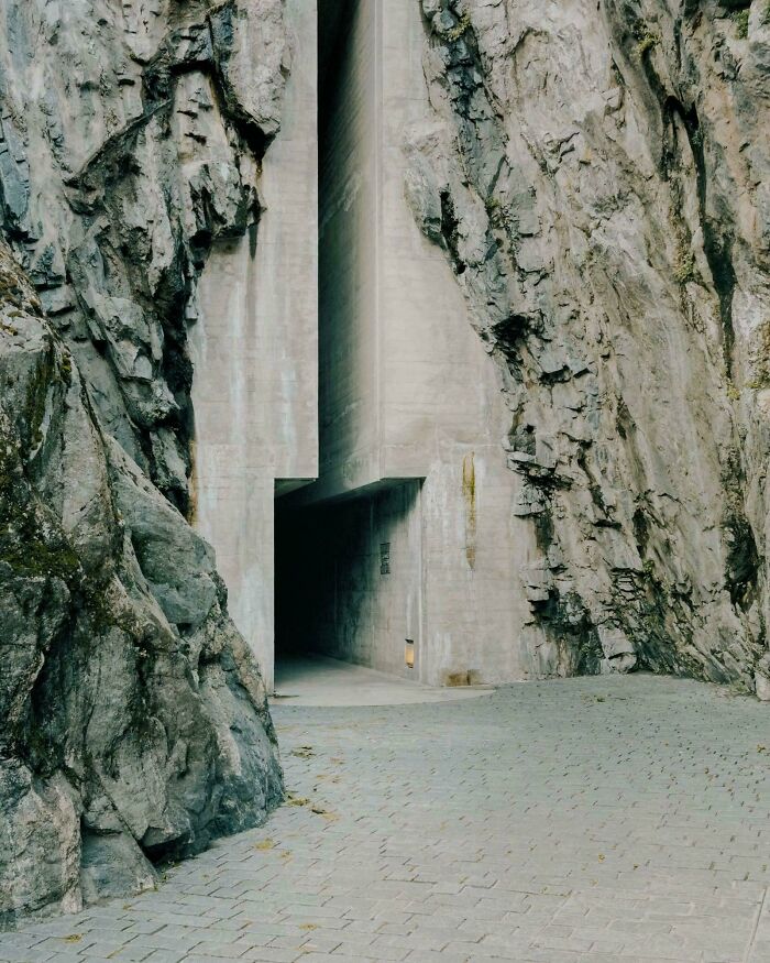 Concrete building entrance embedded in rocky cliffs with an eerie and ominous atmosphere like a supervillain headquarters.