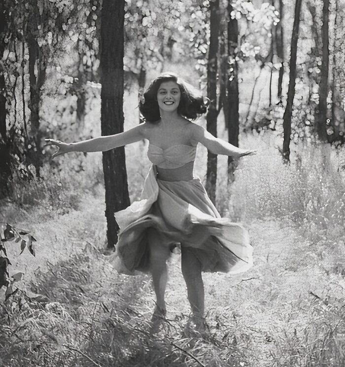 Woman joyfully twirling in a forest, capturing true happiness.