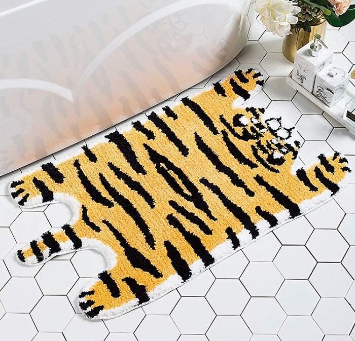 Tiger print bathroom mat on hexagonal tile floor next to white bathtub, enhancing bathroom mats style and decor.