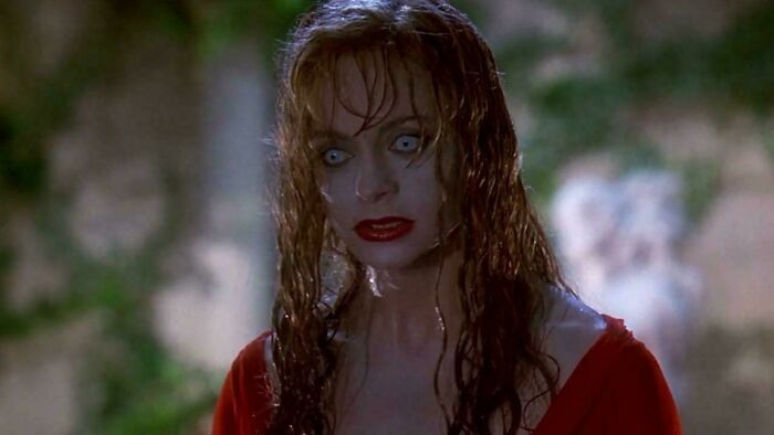 Woman with wet hair and intense expression in '90s themed setting.
