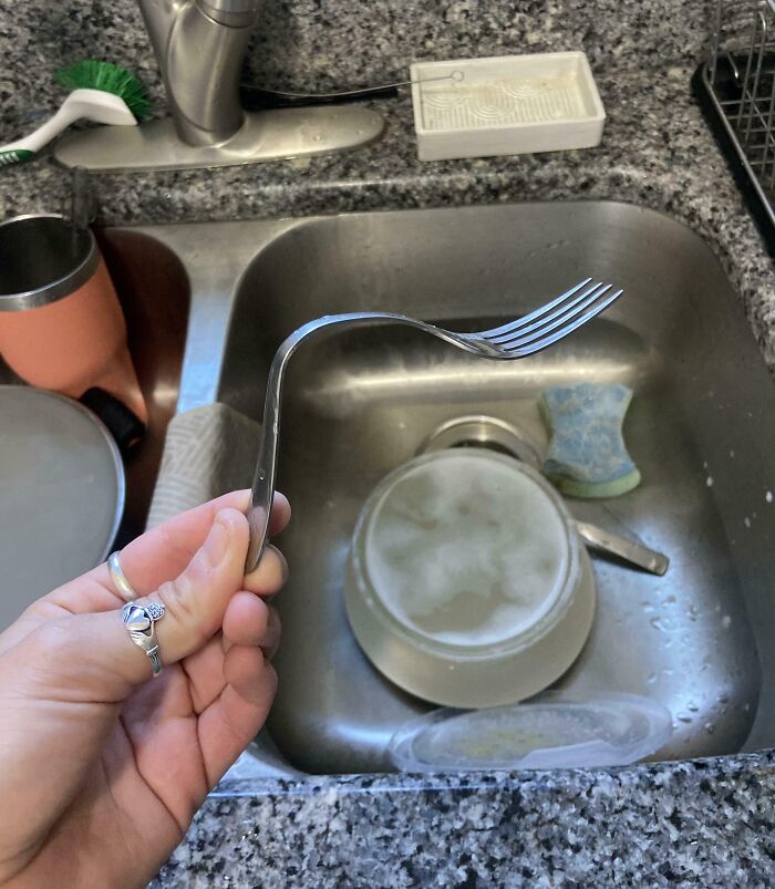 Bent fork held over a kitchen sink, possibly due to annoying boyfriends or husbands prank.