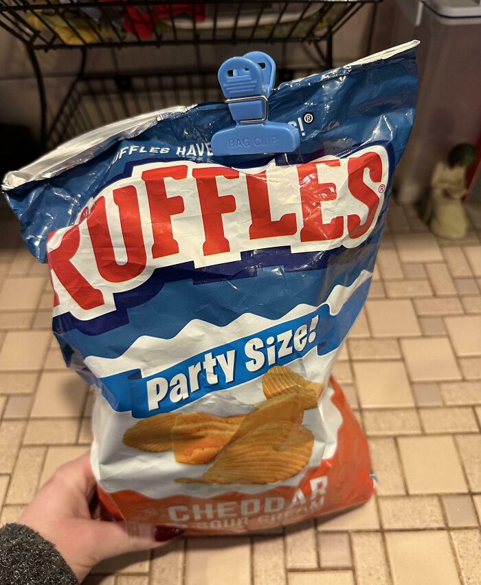"Hand holding a bag of Ruffles, sealed awkwardly with a bag clip, exemplifying annoying boyfriends' habits."