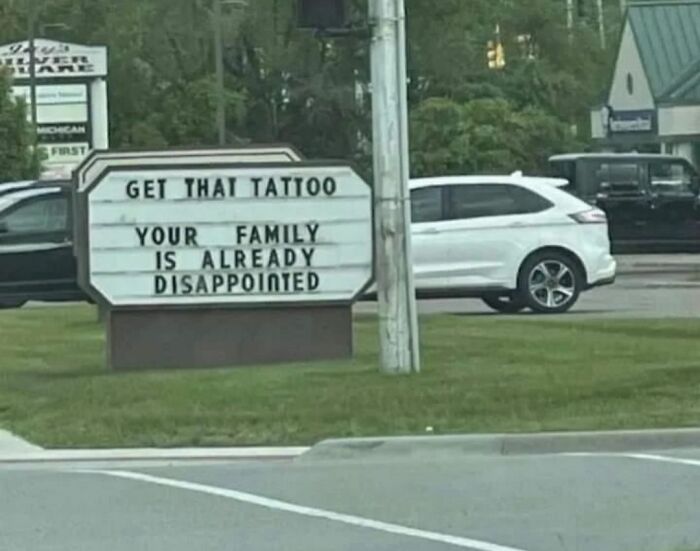 A humorous sign about family disappointment and tattoos, relatable for those barely functioning.
