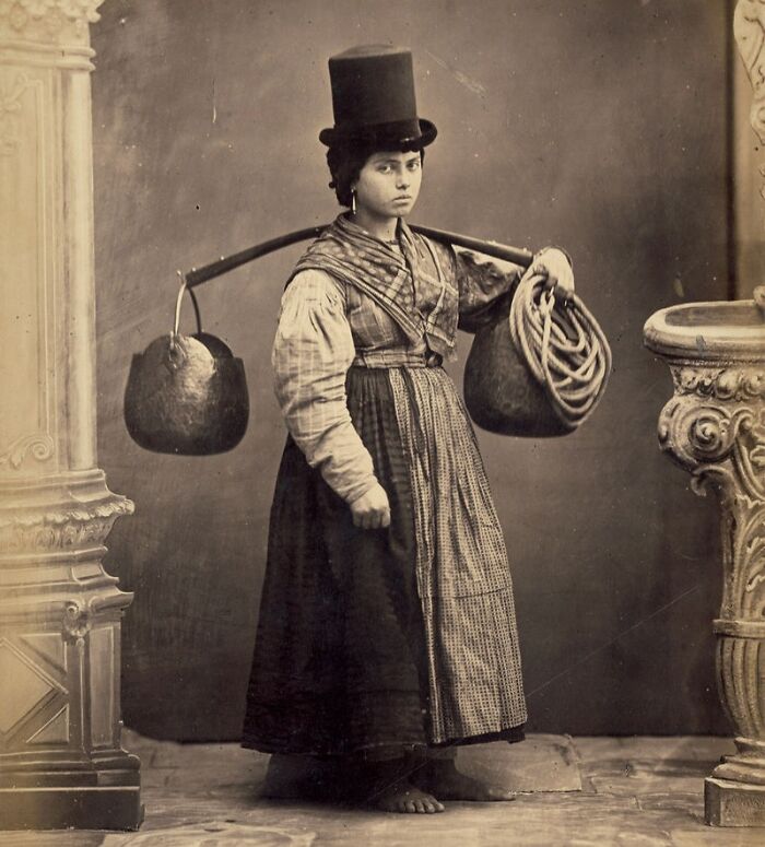 Historic image of a woman with a yoke and buckets, representing jobs that died out as society evolved.