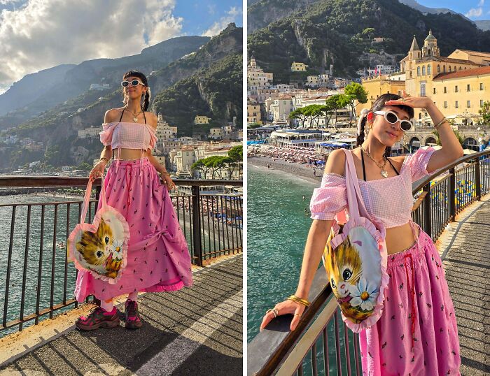 Person in a pink outfit with a cat bag posing by a scenic seaside, showcasing unique fashion risks.