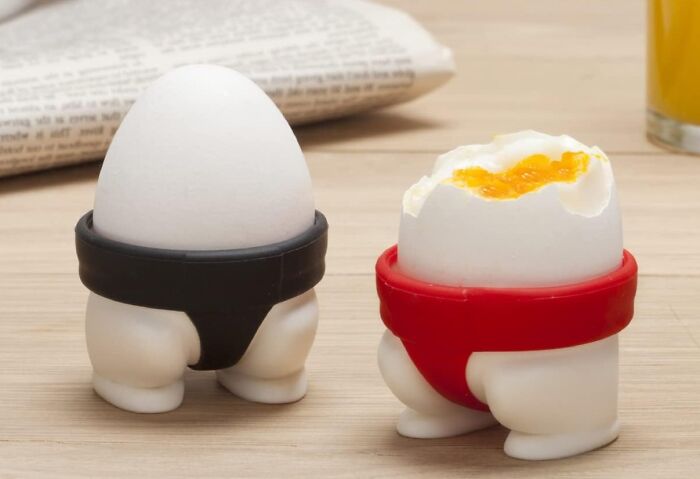Boiled eggs in quirky holders shaped like legs, one with a black band and another with a red band.
