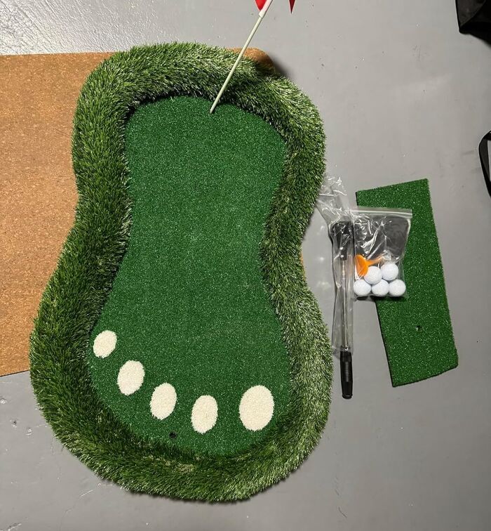 Unique foot-shaped mini-golf putting mat with golf balls and flag, captivating quirky design.