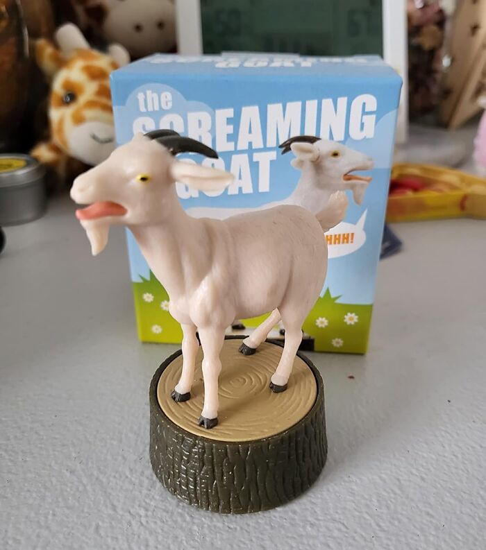 Toy screaming goat figurine on a stump, part of a collection of random things.