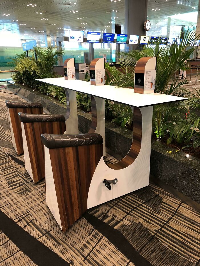 Unique airport seating with foot pedals, offering travelers an interesting experience amidst lush plants.