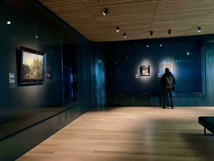 Visitor enjoying art in a dimly lit gallery, creating a serene moment of Tourist-Interesting-Experiences.