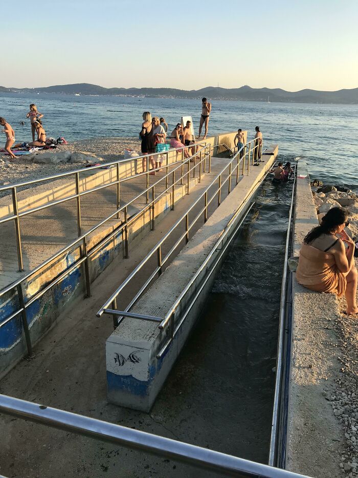 Tourist enjoying interesting experiences by the waterside at sunset with people gathered around a railing walkway.