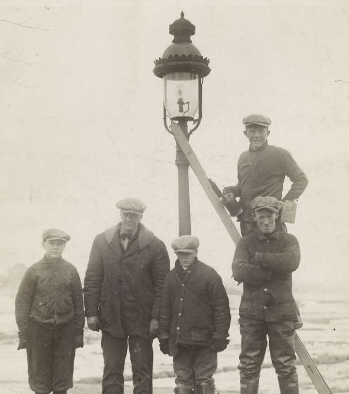 Vintage photo of lamplighters, a job that has died out, posing with a street lamp.