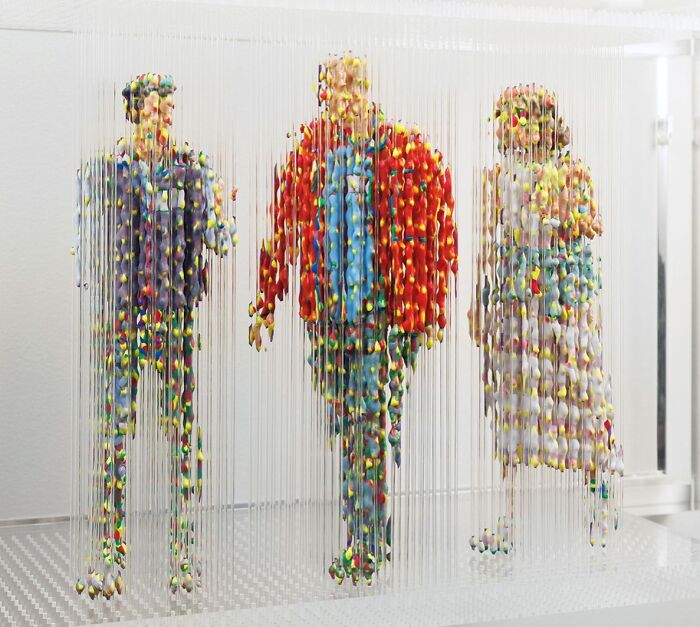 Three-dimensional painting of people by Chris Dorosz, featuring fragmented colorful figures on vertical strands.