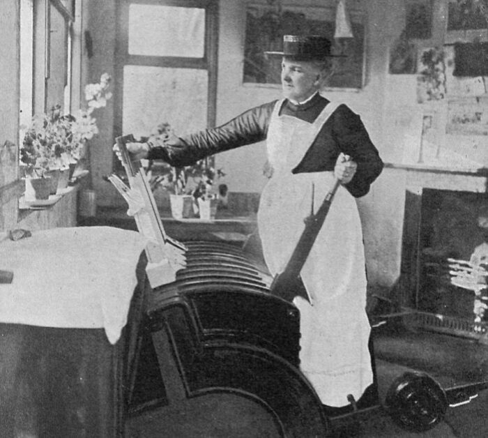 A Victorian woman in an apron operating a mangle, representing jobs that died out as society evolved.
