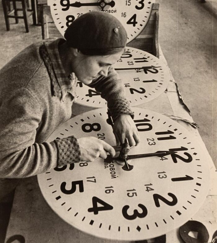 Worker assembling clock faces, representing jobs that died out as society evolved.