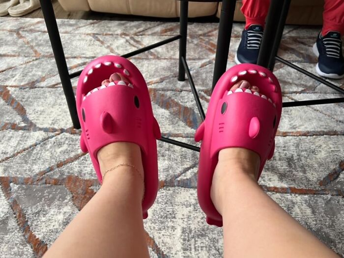 Pink shark-themed slippers on a patterned rug, showcasing random attention-catching footwear design.