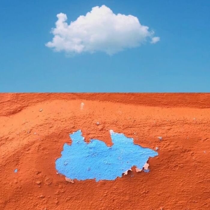 Artistic composition with a cloud above an orange wall and blue paint, capturing extraordinary within the ordinary.