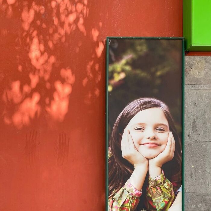 Jose Ruiz González captures a young girl smiling on a vibrant urban backdrop.