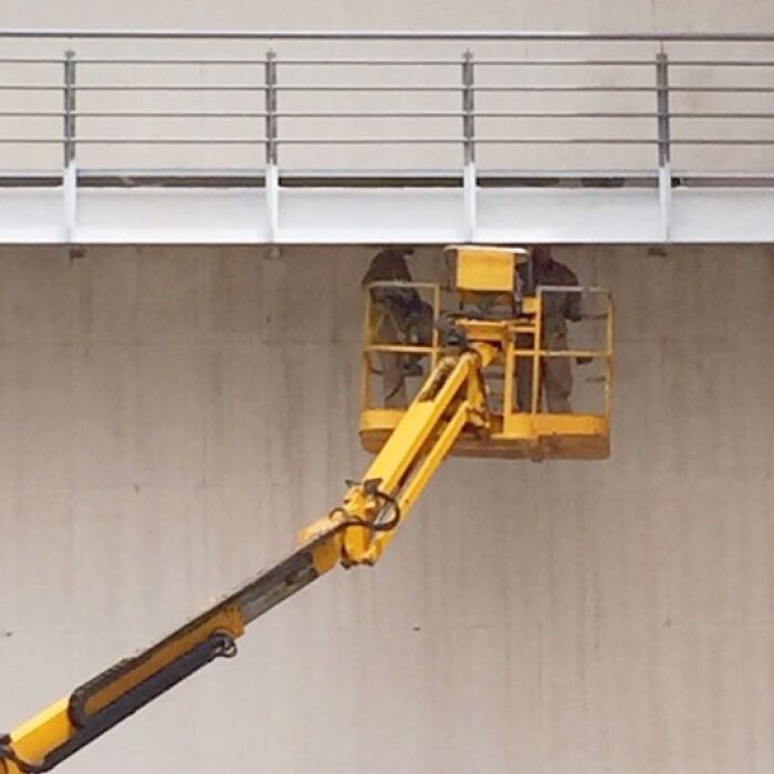 Yellow crane lift with workers capturing ordinary scenes, exemplifying Jose Ruiz González's style.