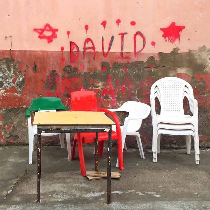 Plastic chairs and a table against a graffiti wall, illustrating Jose Ruiz González's unique photography style.