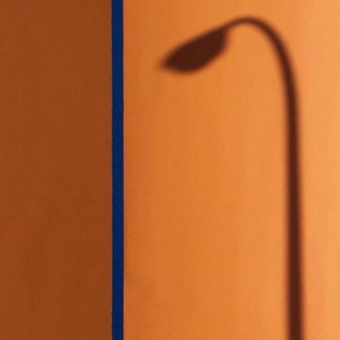 Shadow of a streetlamp on a warm orange wall, captured masterfully by Jose Ruiz González.