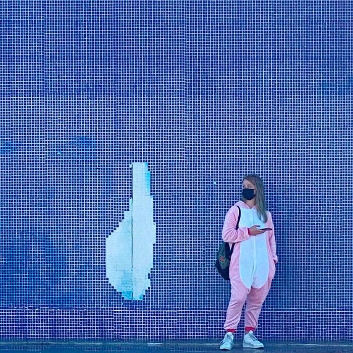 Woman in pink outfit stands against a mosaic wall, captured by Jose Ruiz González, highlighting the extraordinary in the ordinary.