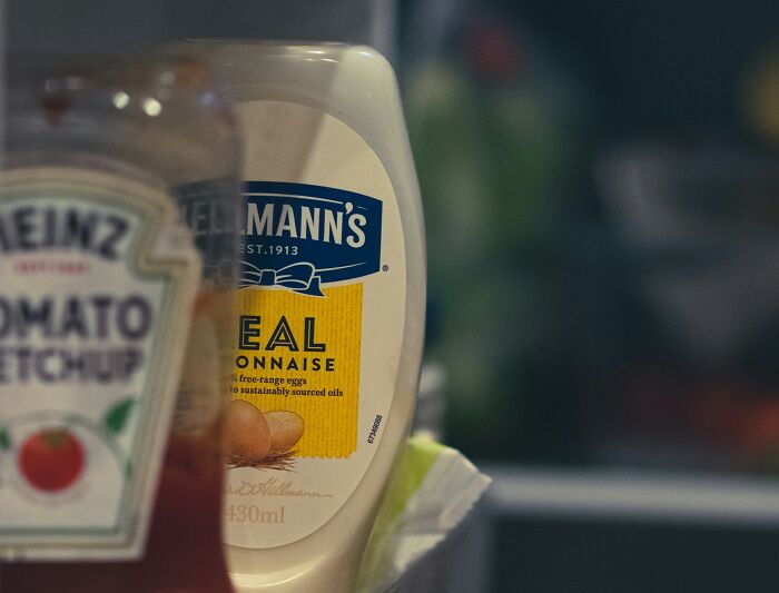 Bottles of ketchup and mayonnaise in a fridge, fitting for hilarious overheard conversations at a picnic.
