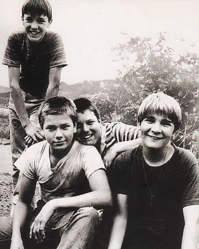 Four boys smiling together outdoors, capturing true happiness.