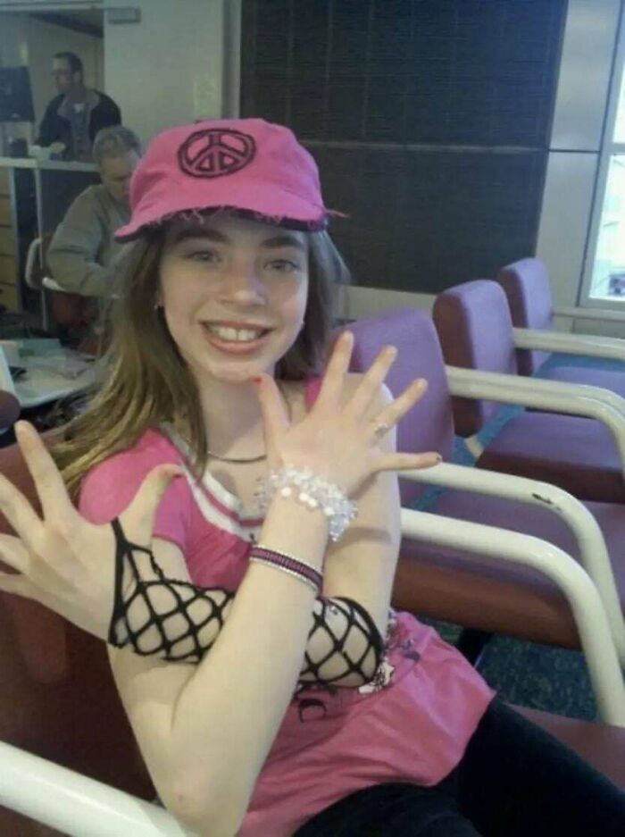 Young woman in a pink hat and fishnet gloves posing awkwardly, a cringe-worthy moment from people's regrettable past.