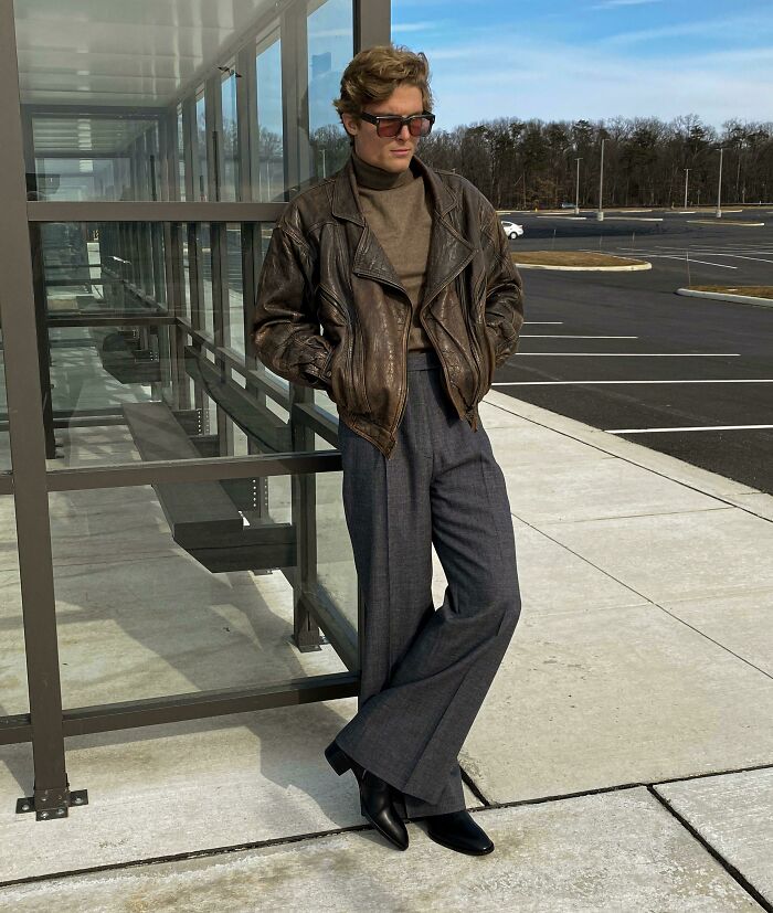 Person wearing a leather jacket and wide-leg trousers, taking a fashion risk successfully.