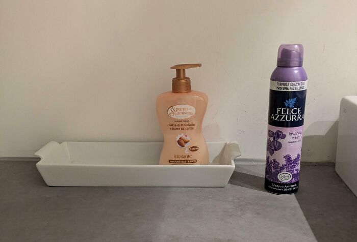 Soap dispenser humorously placed in a long dish, possibly a prank by annoying boyfriends or husbands, next to lavender spray.