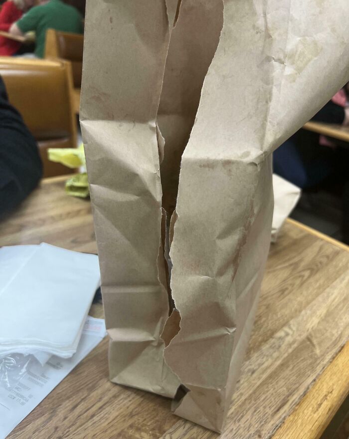 A torn paper bag on a wooden table, possibly left carelessly by annoying boyfriends or husbands.