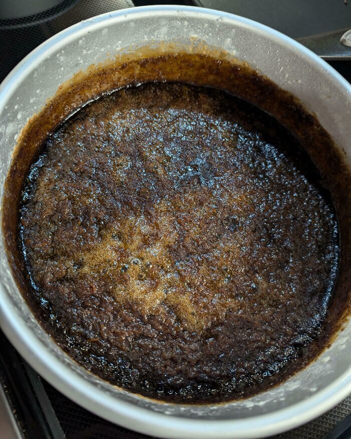 Burnt cake in a baking pan, possibly the result of annoying boyfriends or husbands attempting to bake.