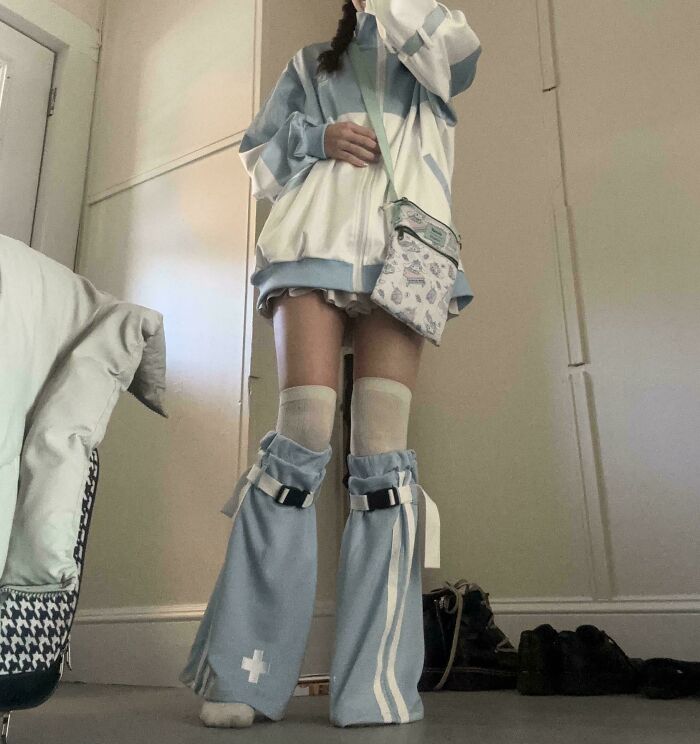 Person wearing a unique fashion outfit with oversized blue knee warmers and a matching jacket. Fashion risks showcased.