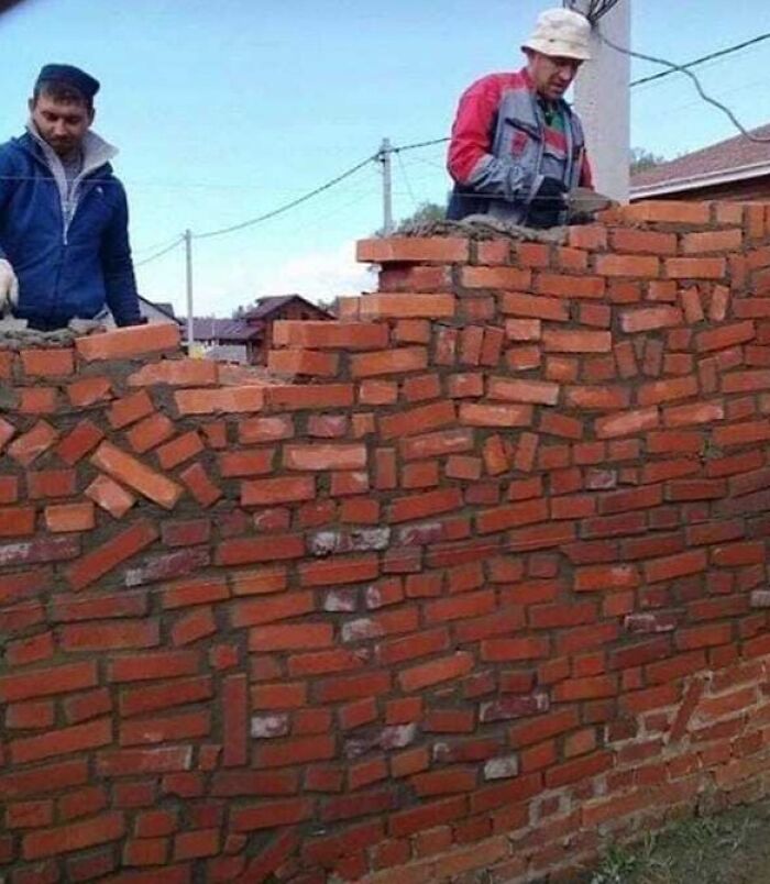 Two workers constructing an uneven brick wall, illustrating architecture fails.