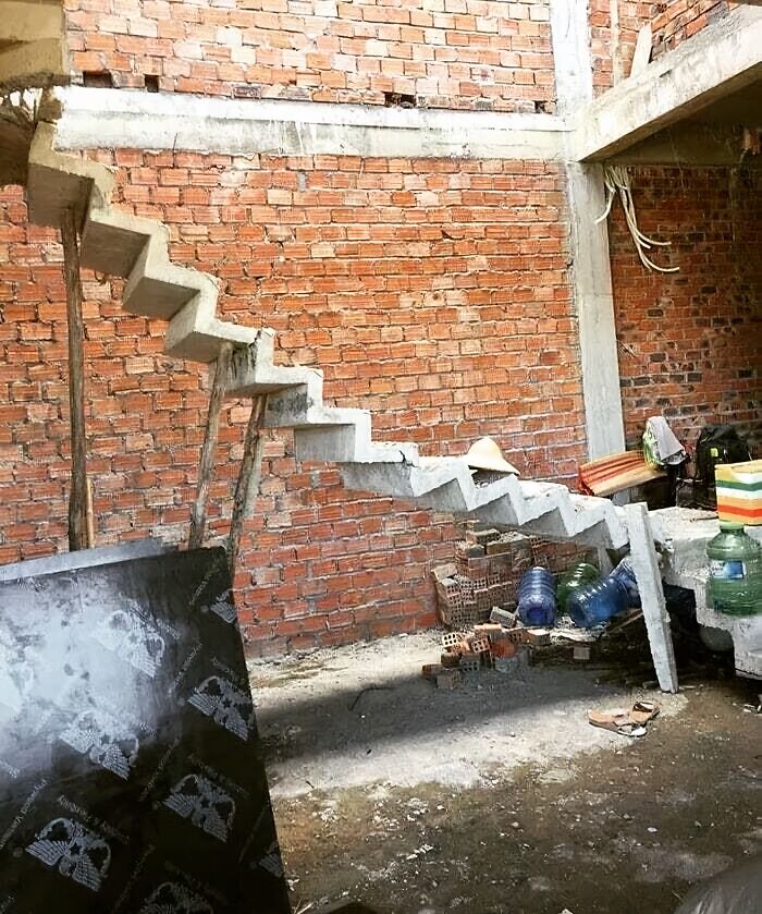 Concrete stairs in a construction site end abruptly against a brick wall, showcasing an architecture fail.
